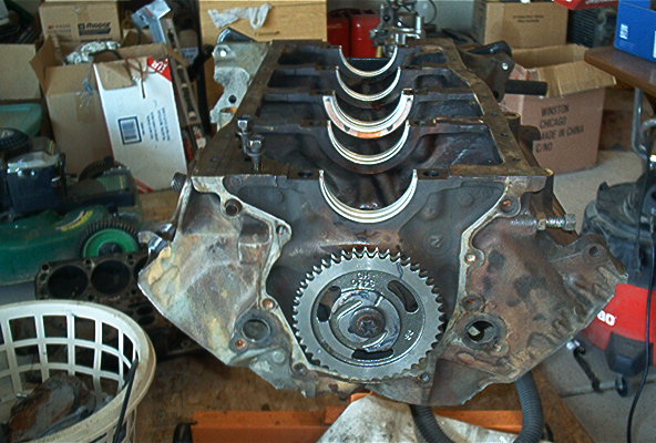 Engine block showing crankshaft gear and main bearing saddles. Some boxes and a lawnmower are in the background