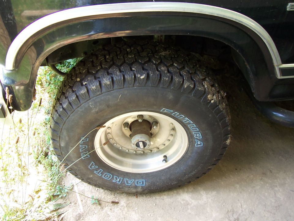 Front wheel of black Ford Bronco with muddy Futura Dakota RVT tire, alloy wheel and manual locking hub