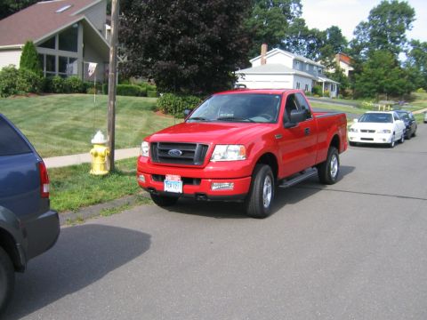 1994 Ford Bronco - Red Ford F-150 pickup truck is parked on a street with other vehicles visible.