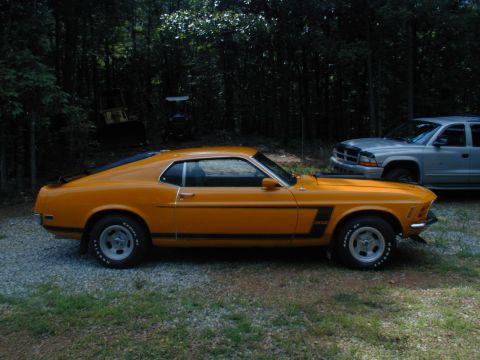 1988 Ford Bronco - A classic orange 1970 Ford Mustang Boss 302 is seen parked outdoors next to a modern silver SUV.
