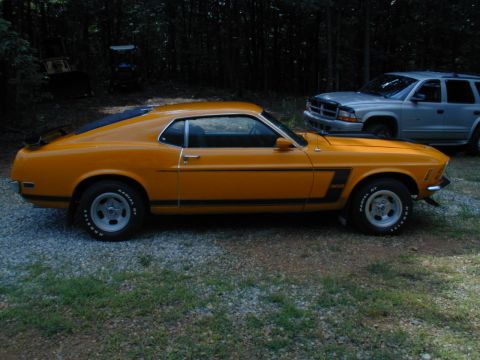 1988 Ford Bronco - This yellow 1970 Ford Mustang Boss 302 is parked next to a silver SUV in a wooded area.