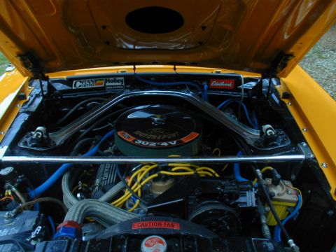 1988 Ford Bronco - Engine bay of a yellow Ford Mustang, a 302-4V V8 engine with aftermarket performance parts.