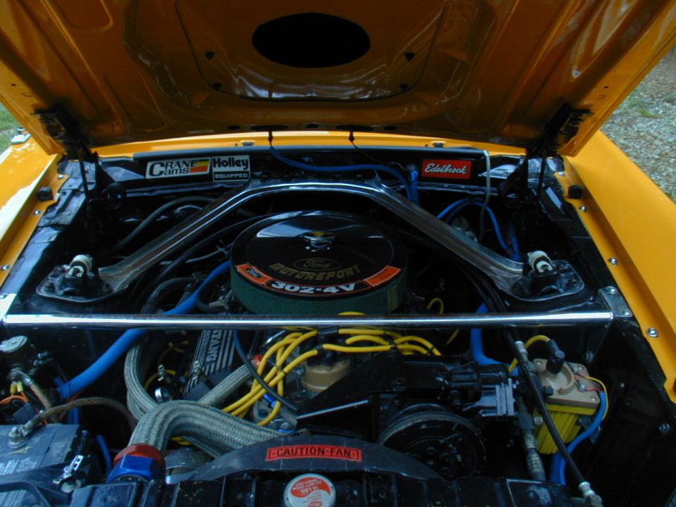 Yellow Ford Mustang engine bay with 302-4V V8, Crane Cams, and Holley parts