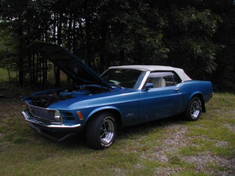 1988 Ford Bronco - A blue 1970 Ford Mustang convertible is parked on grass with its hood open, revealing the engine bay.