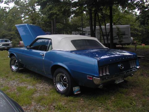 1988 Ford Bronco - A blue convertible Mustang with its hood open sits on a grassy area near an RV.