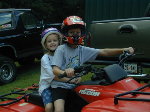 1988 Ford Bronco - Two children ride a red Honda Recon ATV, with a black 1988 Ford Bronco visible in the background.
