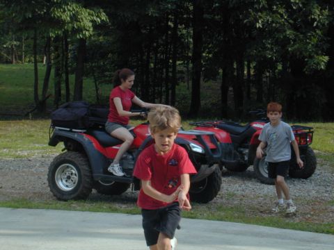 1988 Ford Bronco - Two ATVs are parked outdoors with people around them, with trees in the background.