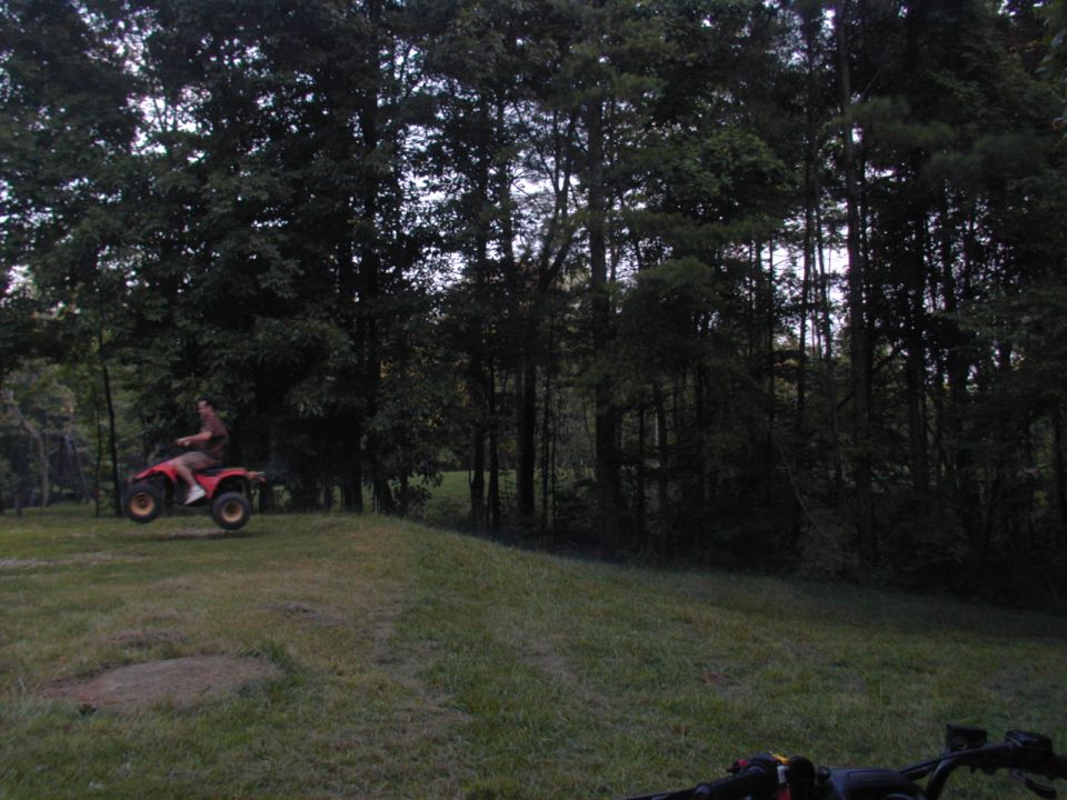 Red ATV airborne over grassy hill
