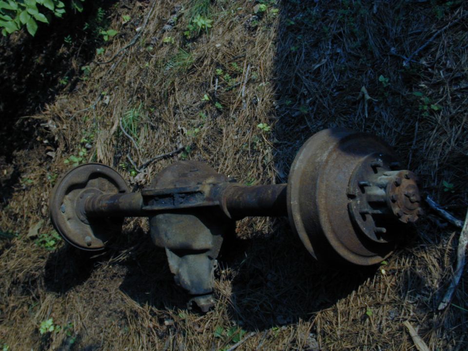 Rusty rear axle assembly with drum brakes and differential housing on the ground
