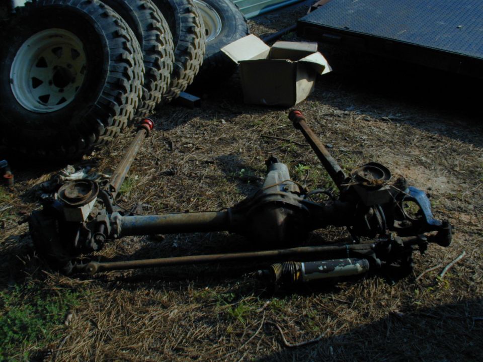 Front and rear axles with tires stacked in background