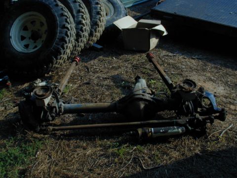 1988 Ford Bronco - Vehicle axles and related parts are displayed outdoors, with a stack of tires visible in the background.
