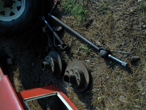 1988 Ford Bronco - Various vehicle axle and brake parts are laid out on the ground, possibly for repair or replacement.