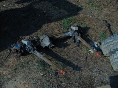 1988 Ford Bronco - Two heavy-duty axles, possibly Dana 44 and Dana 60, are visible on the ground, suggesting a project vehicle.