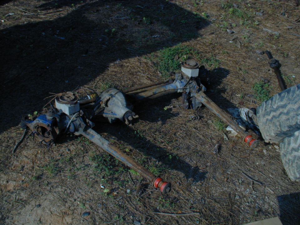 Two heavy-duty axles, likely Dana 44 and Dana 60, lying on the ground