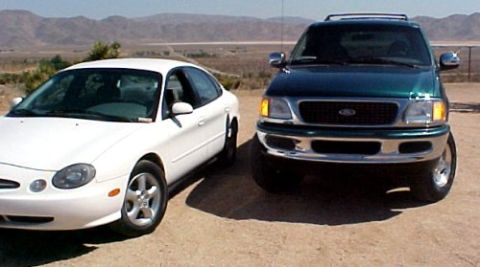 1997 Ford Expedition - Two vehicles are parked on a dirt lot with mountains in the background. The green SUV is in the foreground.