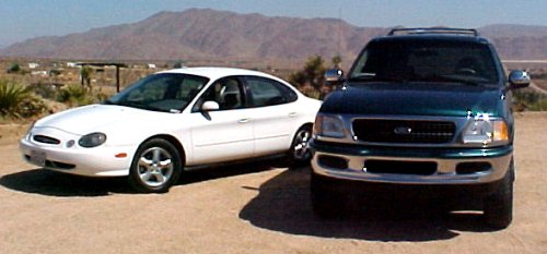 Dark green 1997 Ford Expedition front view, parked next to a white sedan in a desert landscape