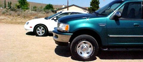1997 Ford Expedition - A 1997 Ford Expedition is parked next to a white sedan in a dry, outdoor lot.