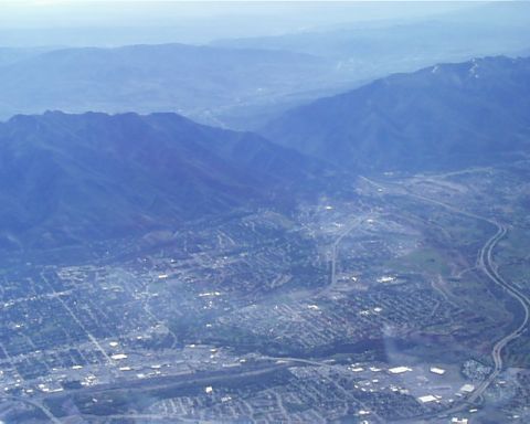 1988 Ford C-350 (Centurion Conversions) - An aerial perspective captures a town situated within a valley, bordered by mountains and traversed by a winding highway.