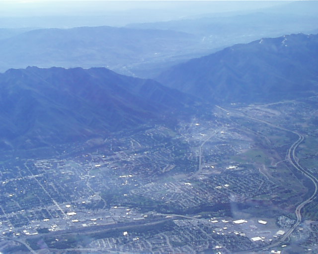 Aerial view of a town in a valley with mountains in the background and a highway running through it