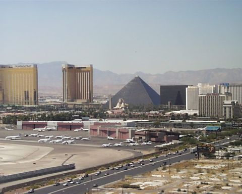 1988 Ford C-350 (Centurion Conversions) - A wide view of the Las Vegas Strip skyline, including the Luxor Pyramid and Mandalay Bay, with an airport tarmac and highway in the foregro…