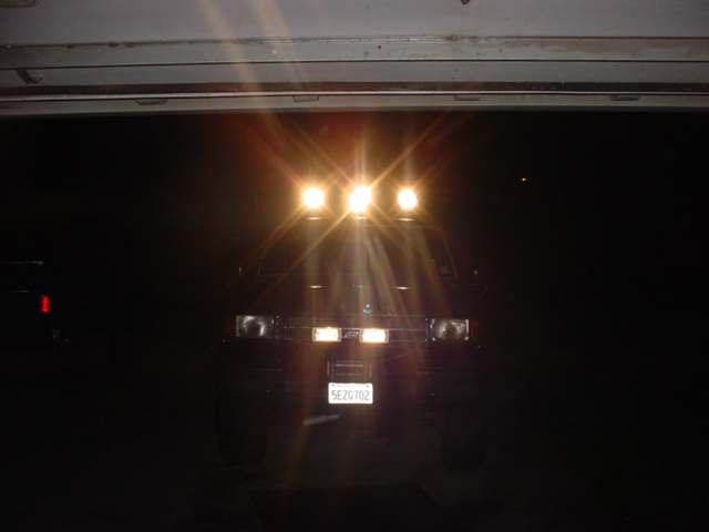Vehicle at night with three roof-mounted off-road lights lit and California plate 5EZG702