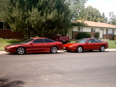 1996 Ford Probe - Two red Ford Probe cars are parked side-by-side on a street in front of a house.