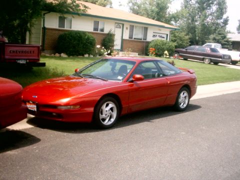 1996 Ford Probe - A red 1996 Ford Probe is parked in a driveway in front of a suburban house.