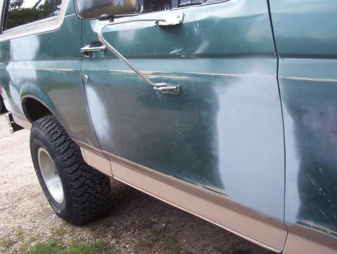 1989 Ford Bronco - Side panel of a 1989 Ford Bronco undergoing bodywork, with primer and sanding marks visible.