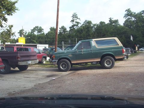 1989 Ford Bronco - A green Ford Bronco is parked in a lot with other vehicles visible.