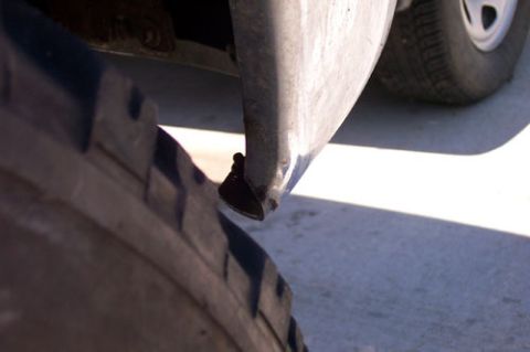 1995 Ford Bronco - Close-up low-angle shot of a large mud-terrain tire's aggressive lug tread crowding the front fender lip and trimmed plastic valance of a l…