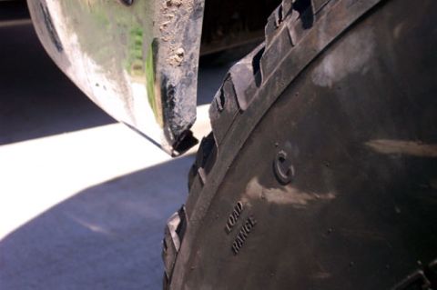1995 Ford Bronco - Extreme close-up of a large off-road tire's sidewall showing aggressive tread lugs and embossed 'LOAD RANGE C' lettering, set against a den…