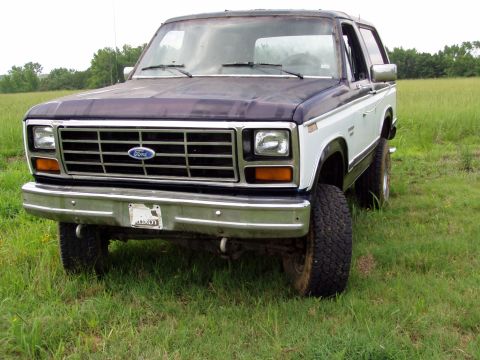 1983 Ford Bronco - This Ford Bronco is parked in a grassy field with trees in the background.
