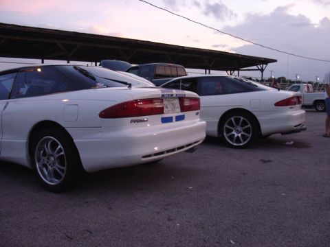 1993 Ford Probe - Two white Ford Probe cars are parked in a lot under a covered structure.