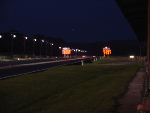 1993 Ford Probe - A drag strip is illuminated by lights and scoreboards at night, with a dark sky overhead.