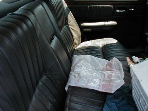 1997 Ford Taurus - The interior of a 1997 Ford Taurus shows black leather seats and a plastic bag on the passenger seat.
