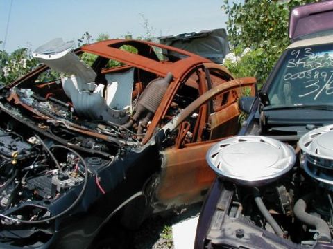1997 Ford Taurus - Junked car showing interior damage and engine bay. Another vehicle is parked nearby.