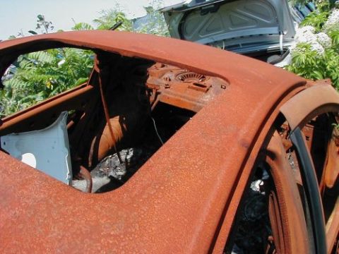1997 Ford Taurus - The interior of a heavily rusted vehicle is visible, with another car's trunk open in the background.