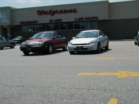 1997 Ford Taurus - A red 1997 Ford Taurus is parked in front of a Walgreens, alongside another vehicle.