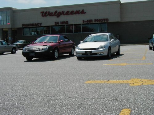 Red 1997 Ford Taurus with a black car bra parked in front of a Walgreens