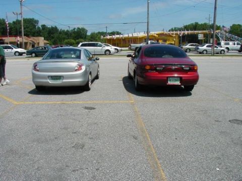 1997 Ford Taurus - A red sedan is parked in a lot, showing its rear end and license plate.