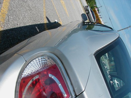 silver sedan's rear quarter panel and taillight, another car in background