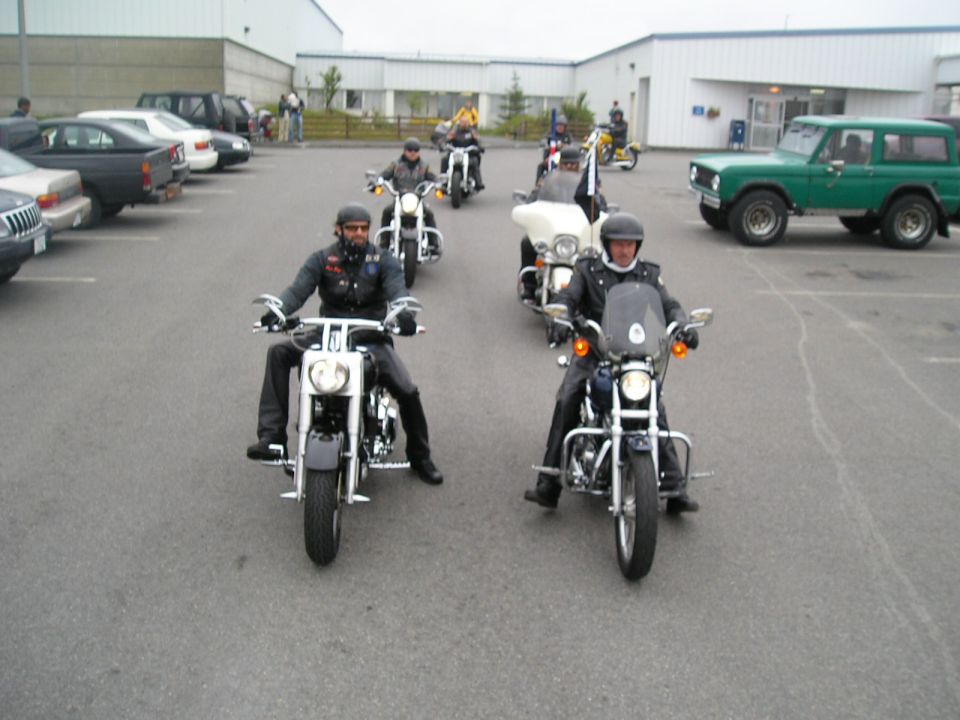 Motorcyclists in parking lot with green Ford Bronco parked at right