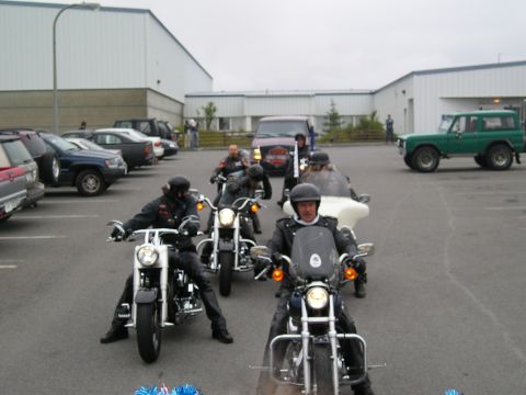 1996 Ford Bronco - A group of motorcyclists ride in formation past a green Ford Bronco.