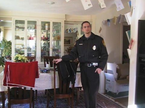 2000 Jeep Liberty - A man in a police uniform stands in a dining room, with a china cabinet visible in the background.