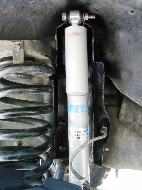 1985 Ford Bronco - Close-up view of a vehicle's suspension system, showing a shock absorber and coil spring.