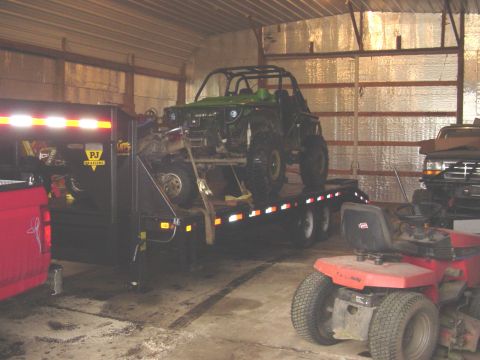 1992 Ford Bronco - A green off-road vehicle is loaded onto a trailer inside a barn, with other vehicles visible.