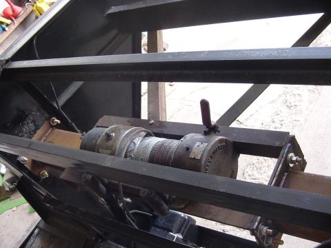 1992 Ford Bronco - Close-up view of a heavy-duty winch with cable wound around the drum, mounted on a metal structure.