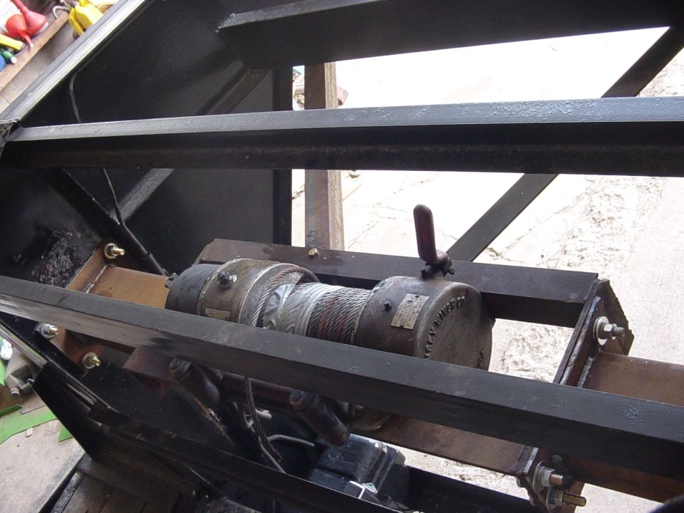 Winch mounted on metal frame, possibly for a trailer or truck bed