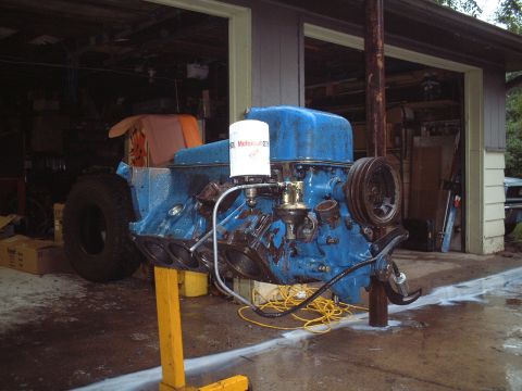 1967 Ford Galaxie - Engine block painted blue with an oil filter attached, resting on a stand in a garage.