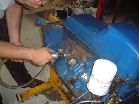 1967 Ford Galaxie - A mechanic works on a blue engine block, which has a Motorcraft oil filter attached.